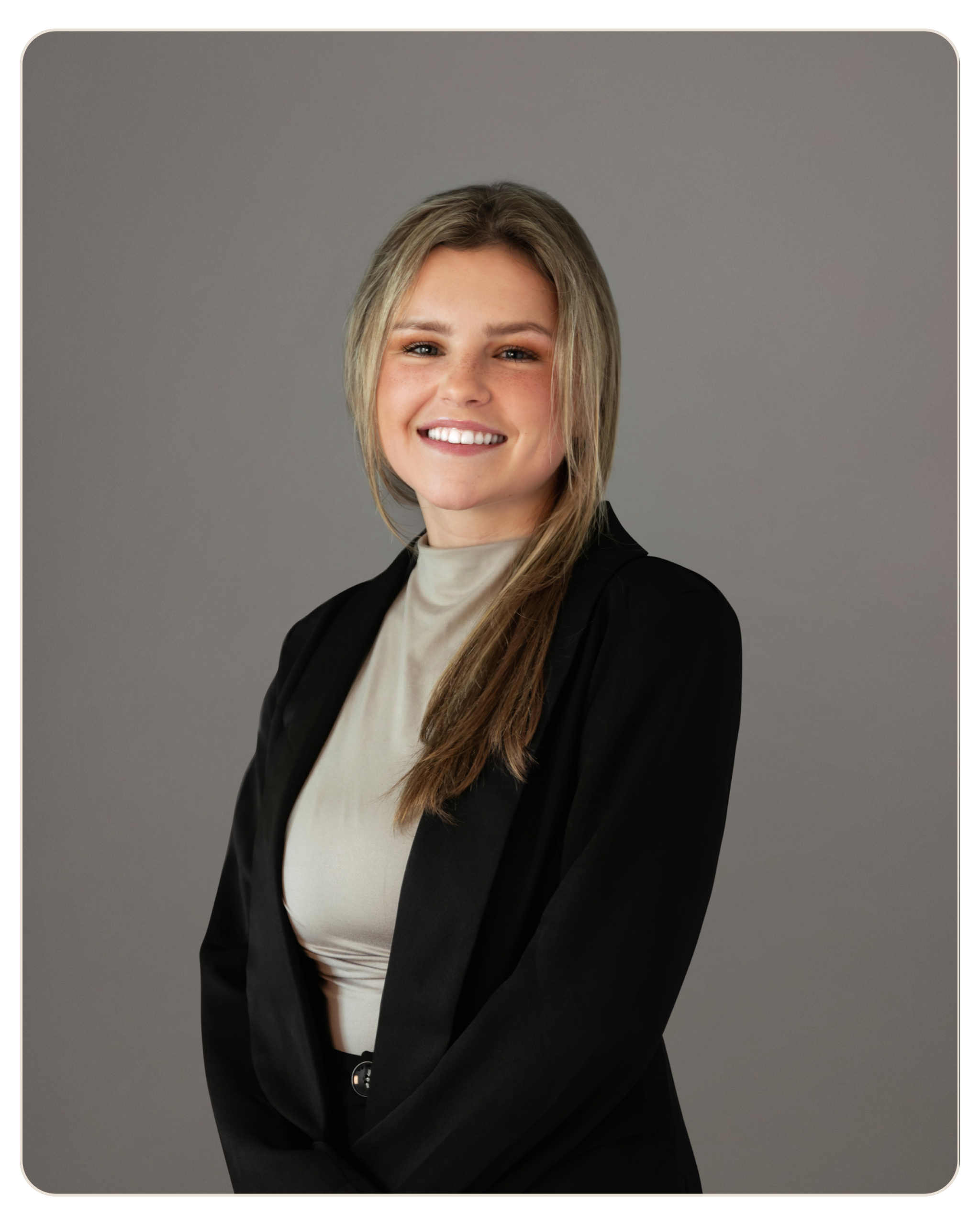 MaryJo Yarbrough Smiling woman in a black blazer and beige blouse, posing against a neutral grey studio backdrop.
